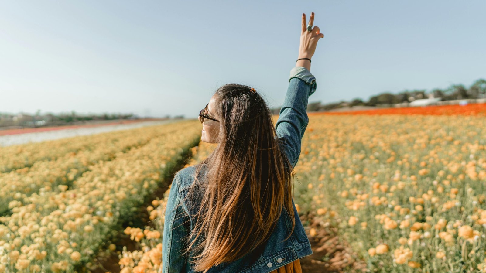 A woman enjoying a sunny day in a vivid yellow flower field in Carlsbad, CA.