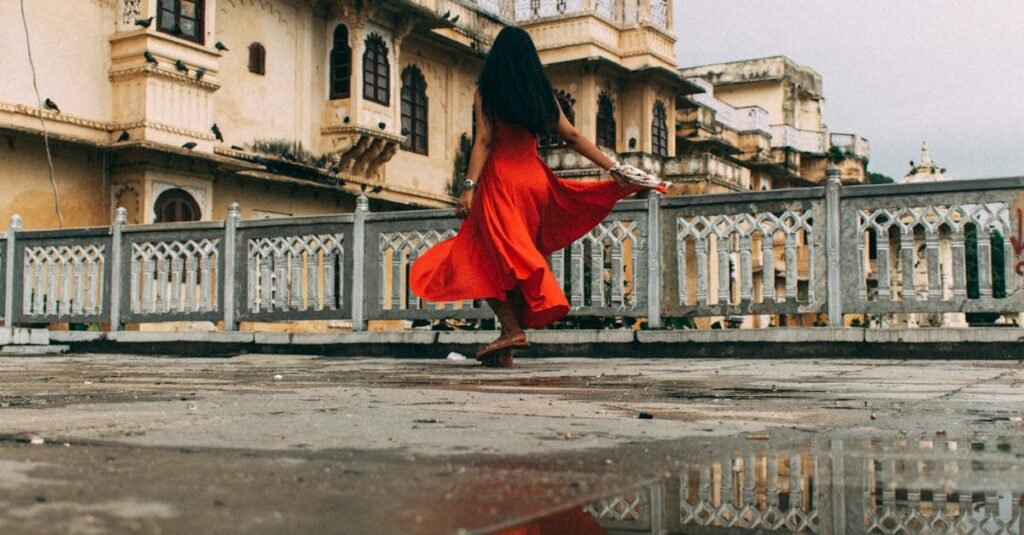 A woman in a red dress walks through the palatial architecture of Udaipur, India.